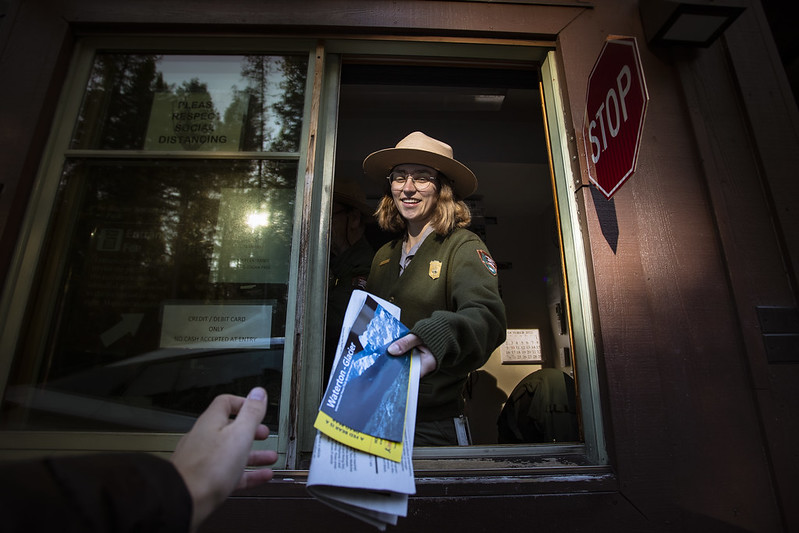 A park ranger welcomes a visitor to Glacier National Park with a map